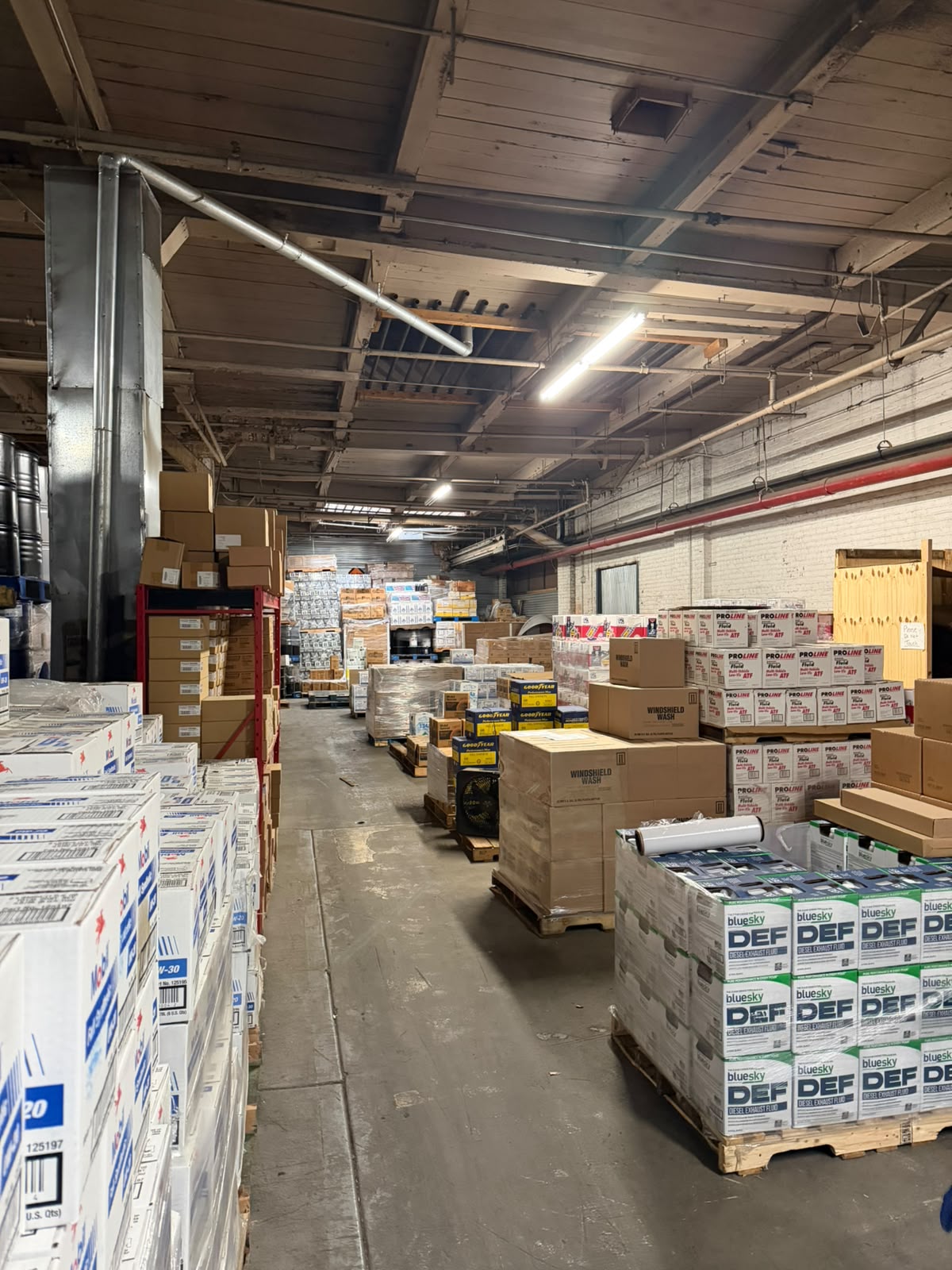 A long warehouse aisle with Blue Sky DEF and Proline ATF pallets