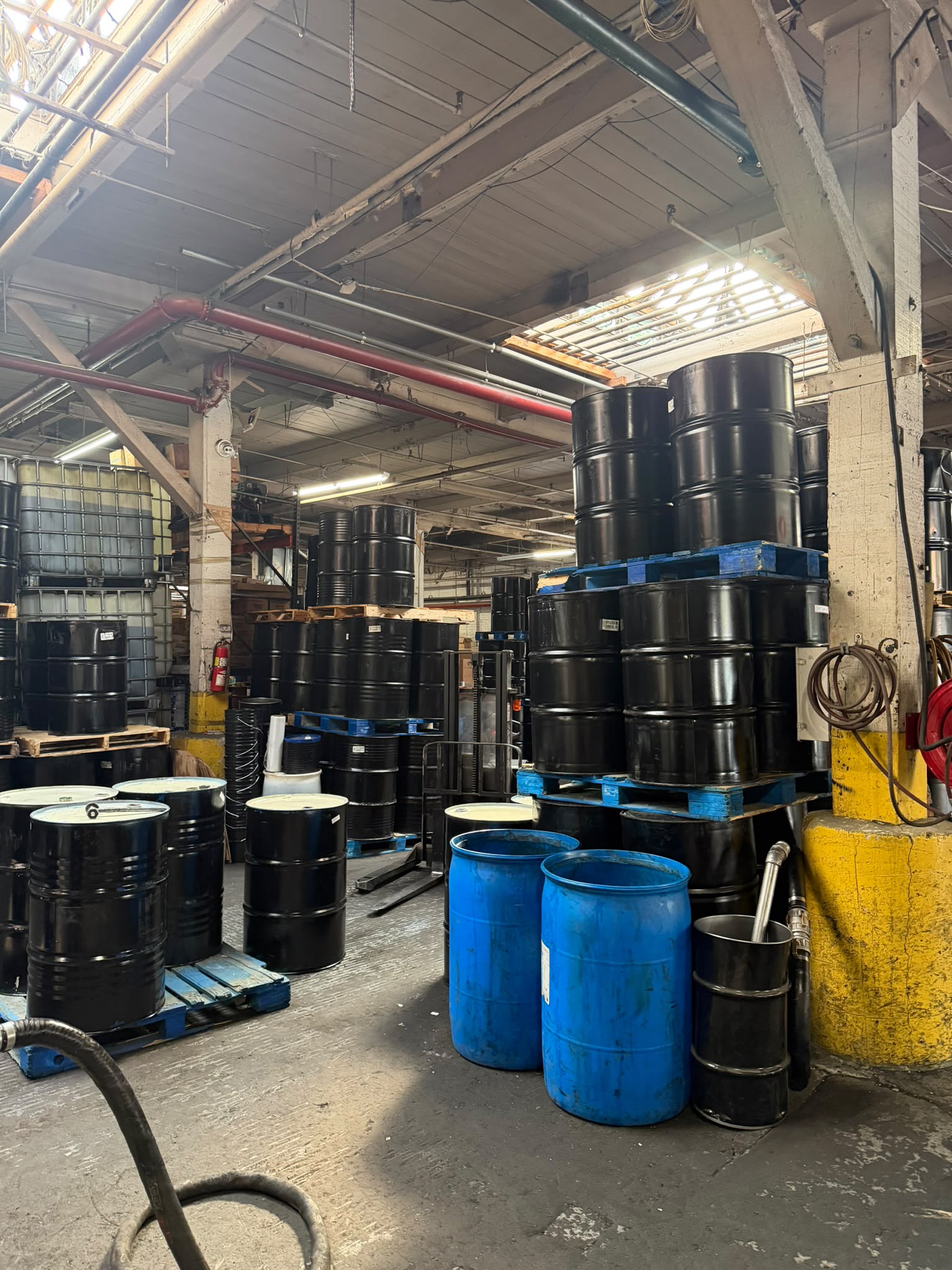 Tall stacks of black drums in the Bass Oil warehouse