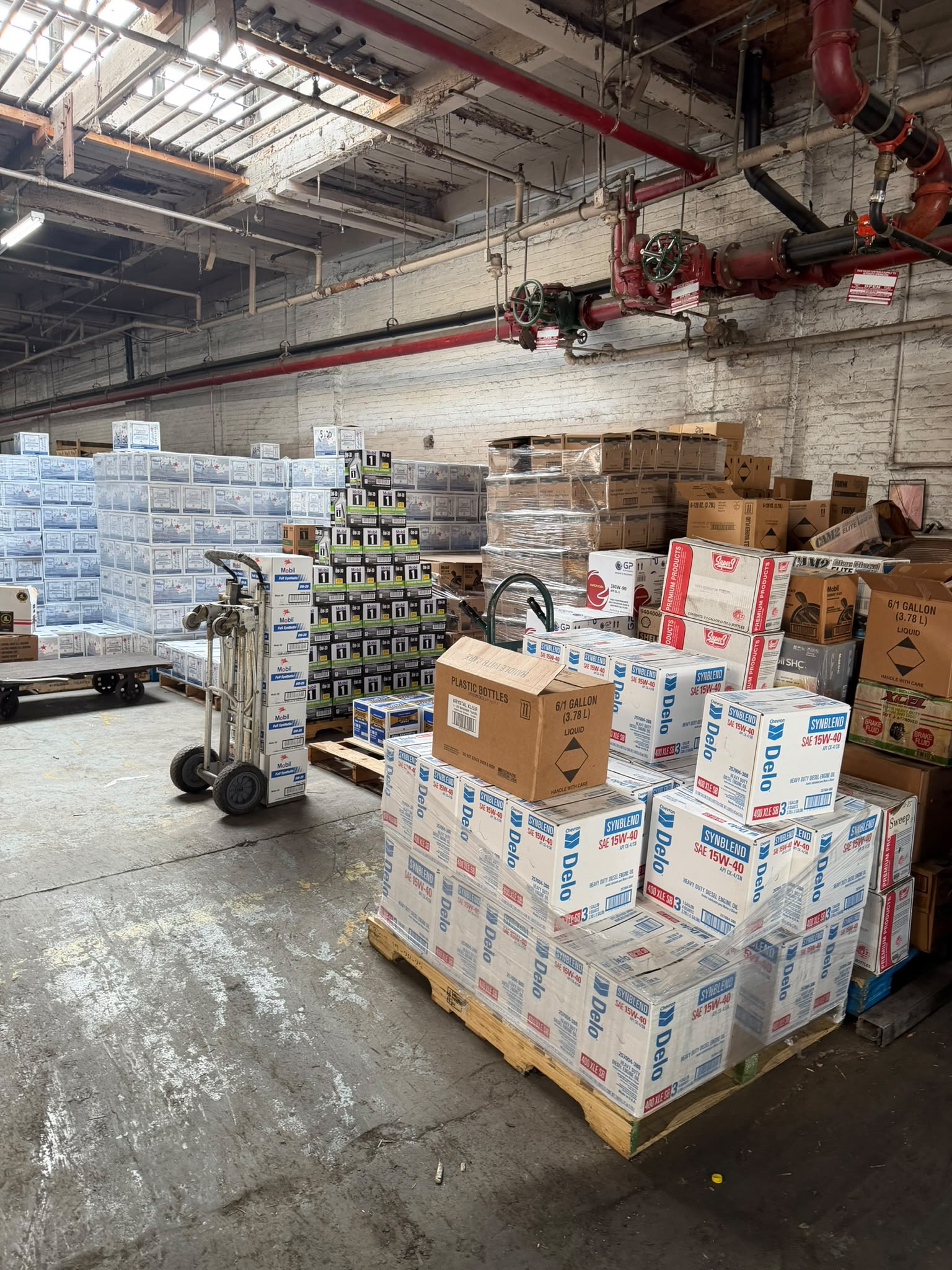 Warehouse aisle lined with stacked cases of Delo and Mobil oils